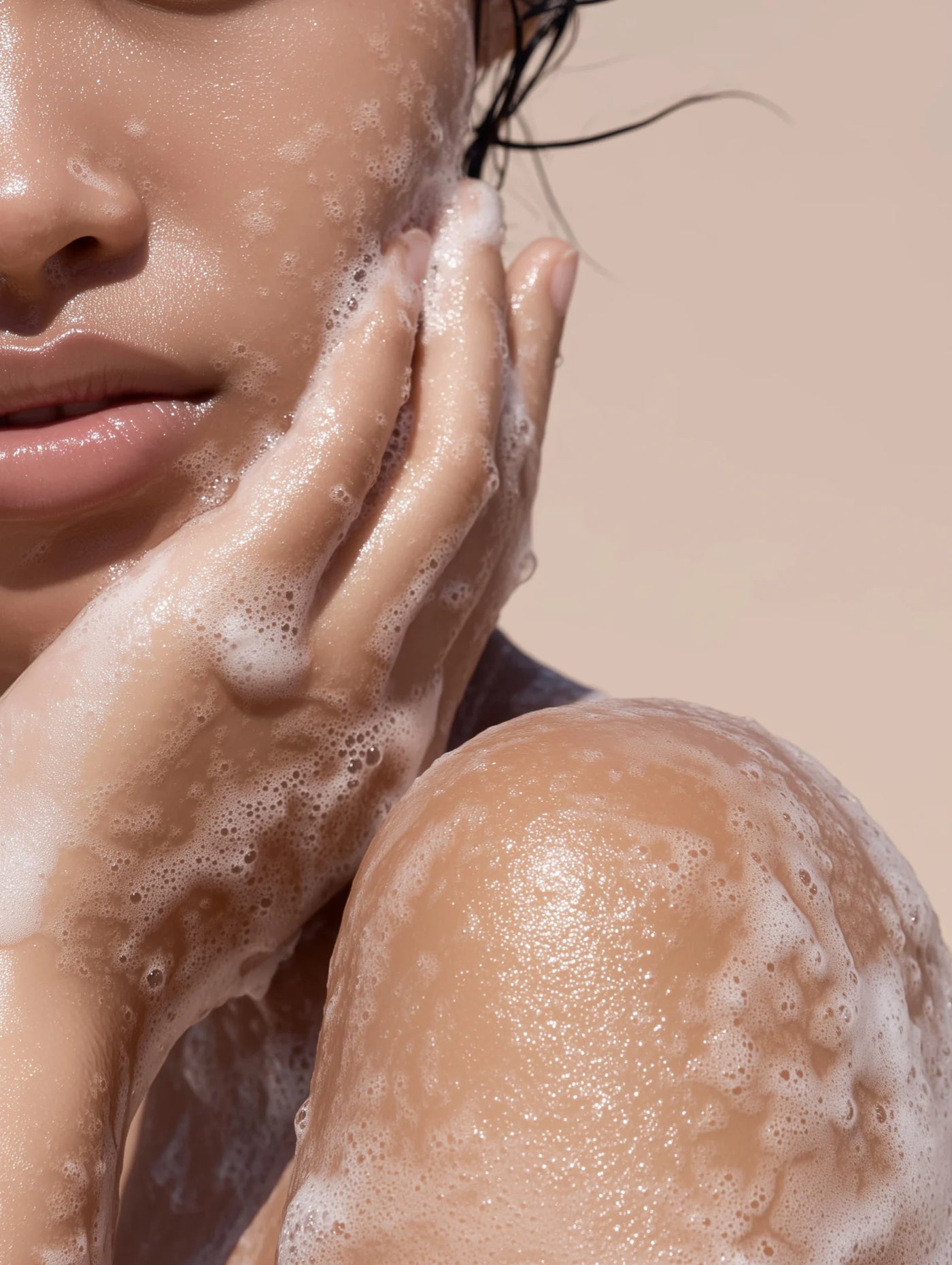 Close-up of a person washing their face with soap bubbles on a beige background