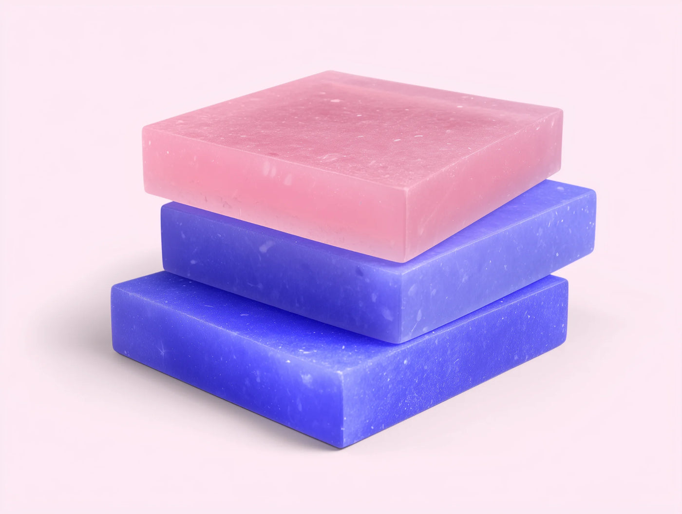 Three bars of soap in pink, purple, and blue on a light purple background