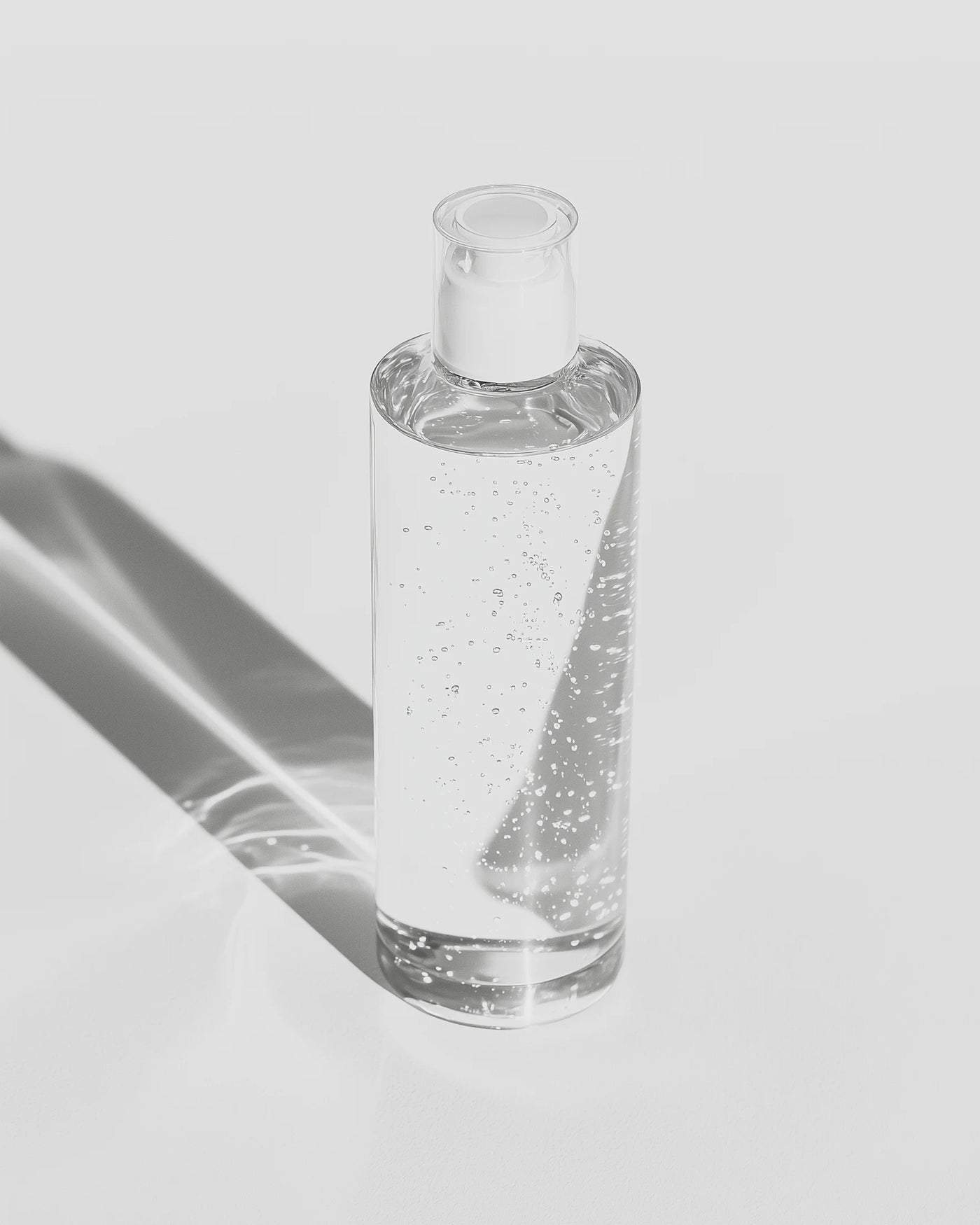 Clear glass bottle with a dropper on a light gray background