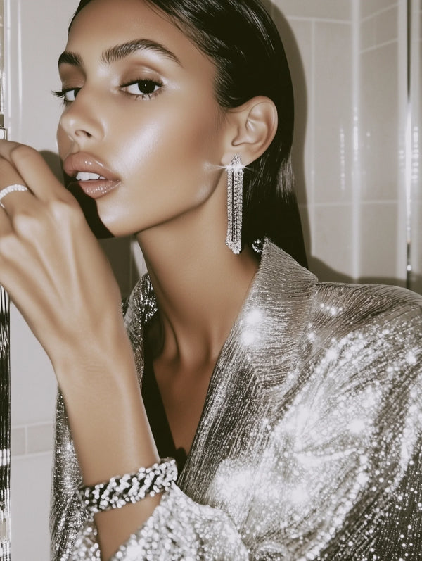 Woman wearing a sparkling silver outfit with long earrings in a bathroom setting