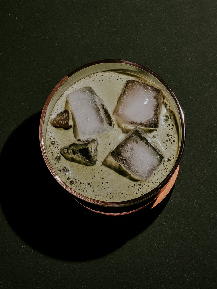 Copper cup with iced matcha and ice cubes on a dark background