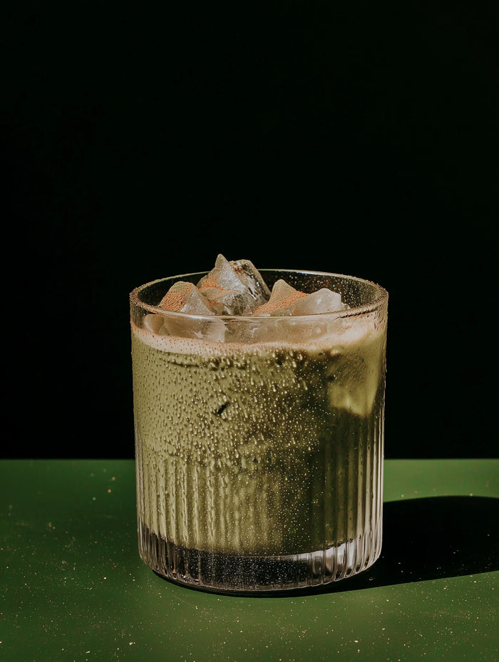 Green cocktail with ice in a glass on a dark background