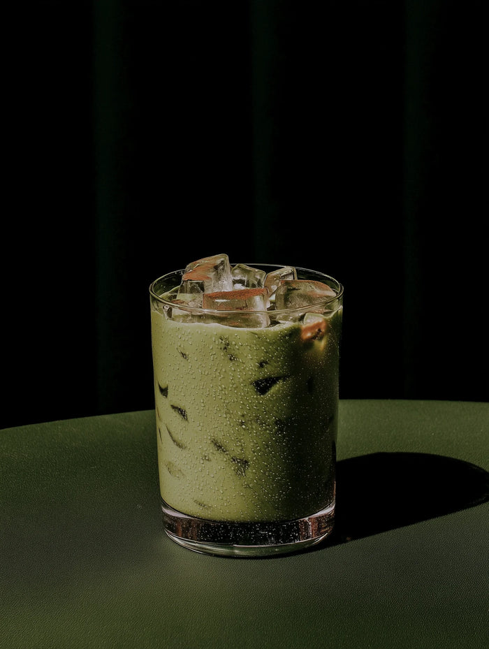 Glass of iced matcha with ice cubes on a dark background