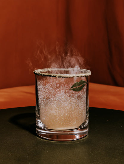 Glass with a leaf design on a dark surface against a brown background