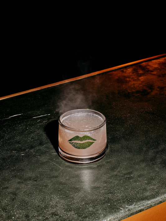 Cocktail in a glass with a logo on a dark surface