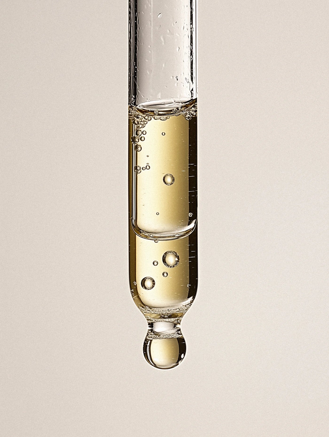 Close-up of a test tube with liquid dripping against a neutral background