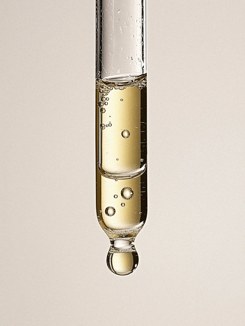 Close-up of a test tube with liquid dripping against a neutral background
