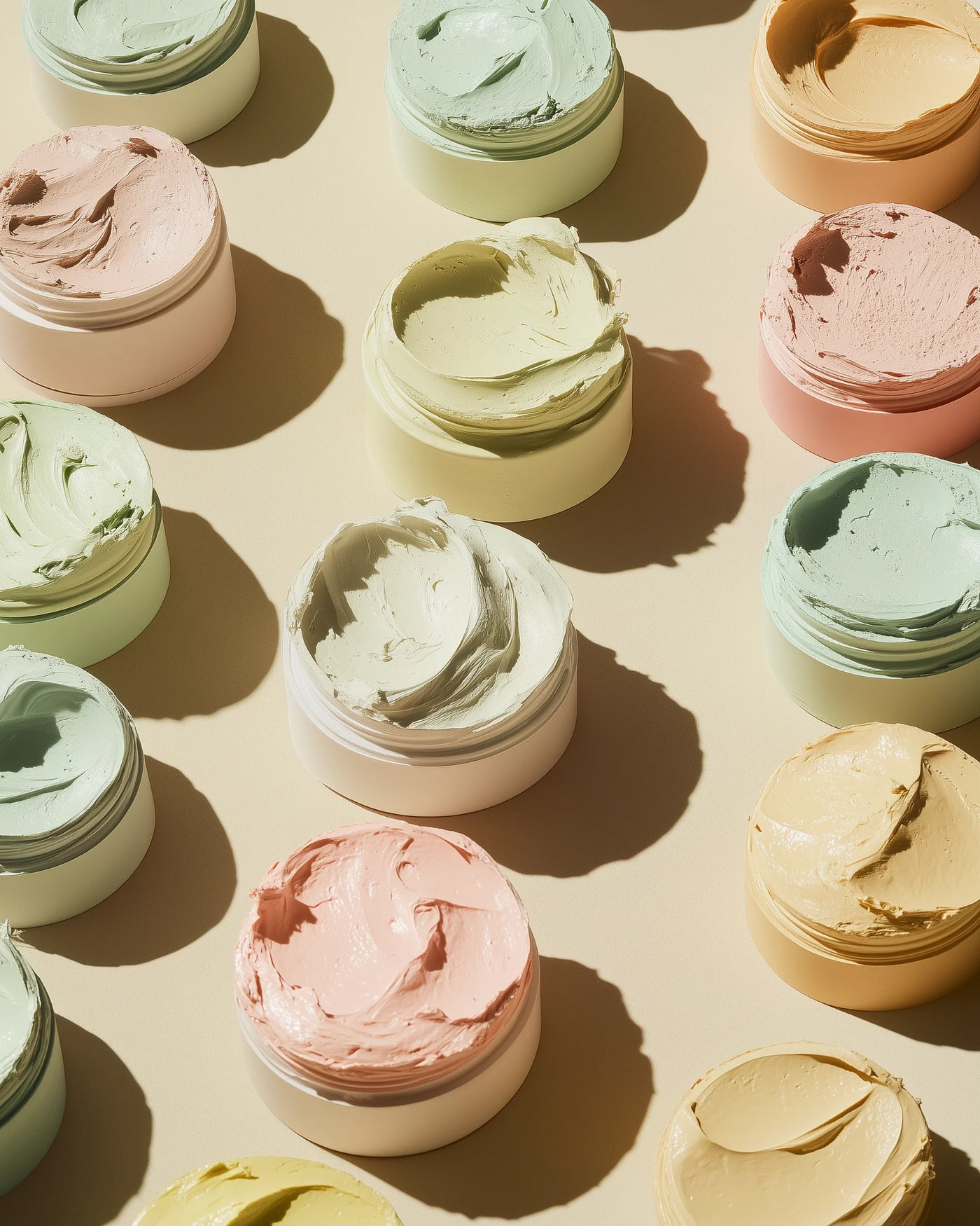 Jars of cream in various colors arranged on a beige background